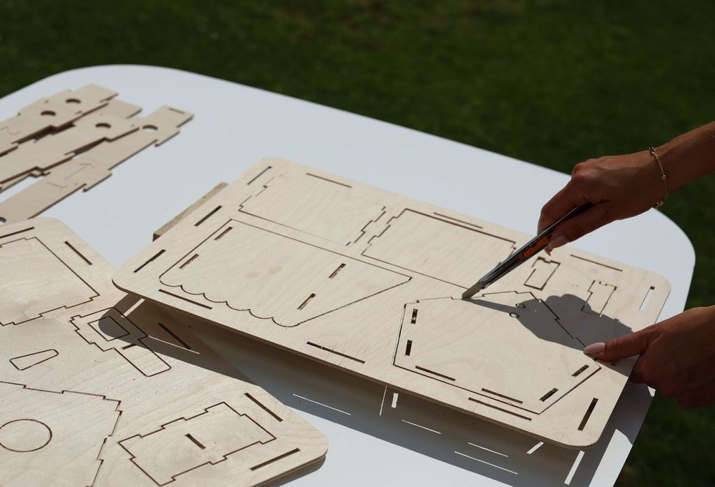 Releasing pre-cut bird feeder parts from the plywood packaging with a utility knife